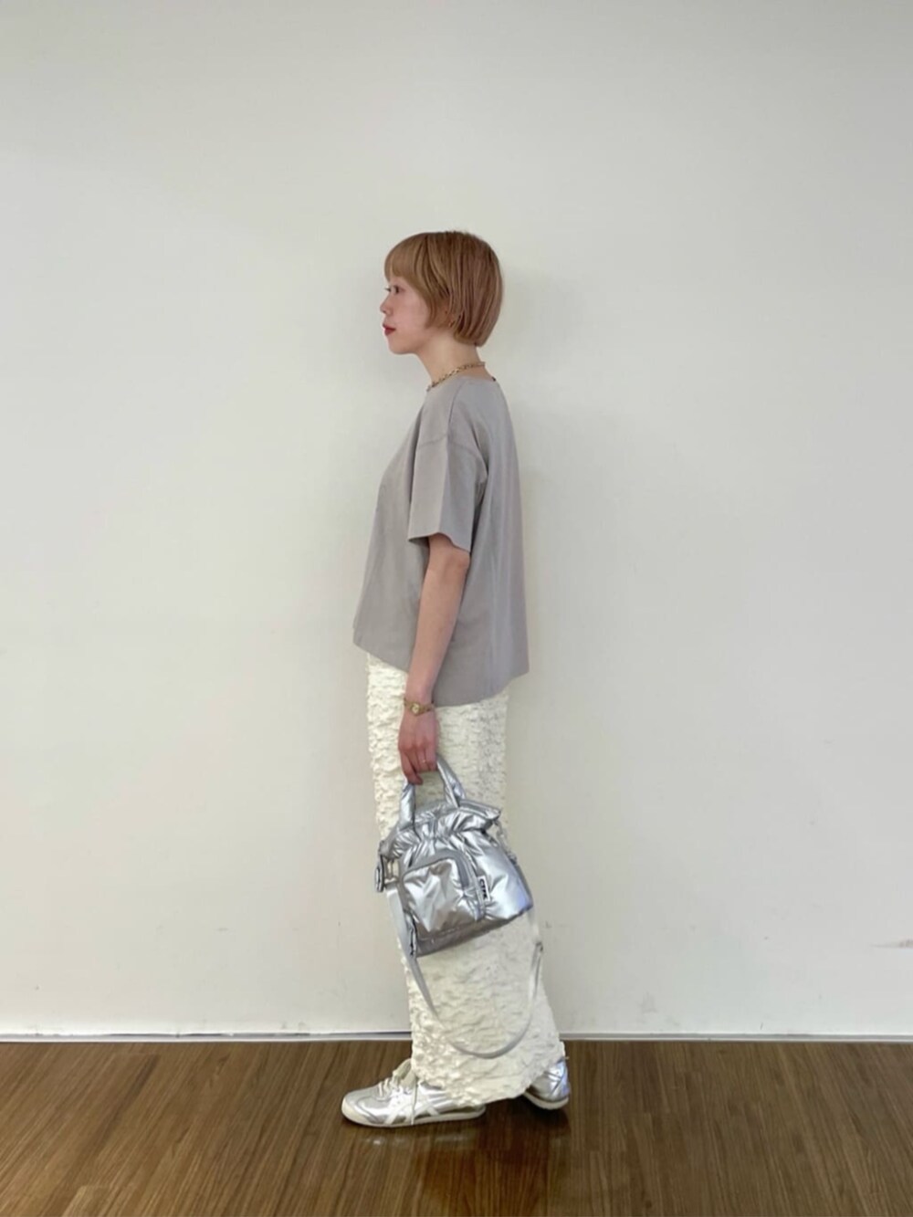 シルバー系のハンドバッグ、ホワイト系のスカート、グレー系のTシャツ/カットソーを着用したレディースの春コーディネートの2枚目の写真