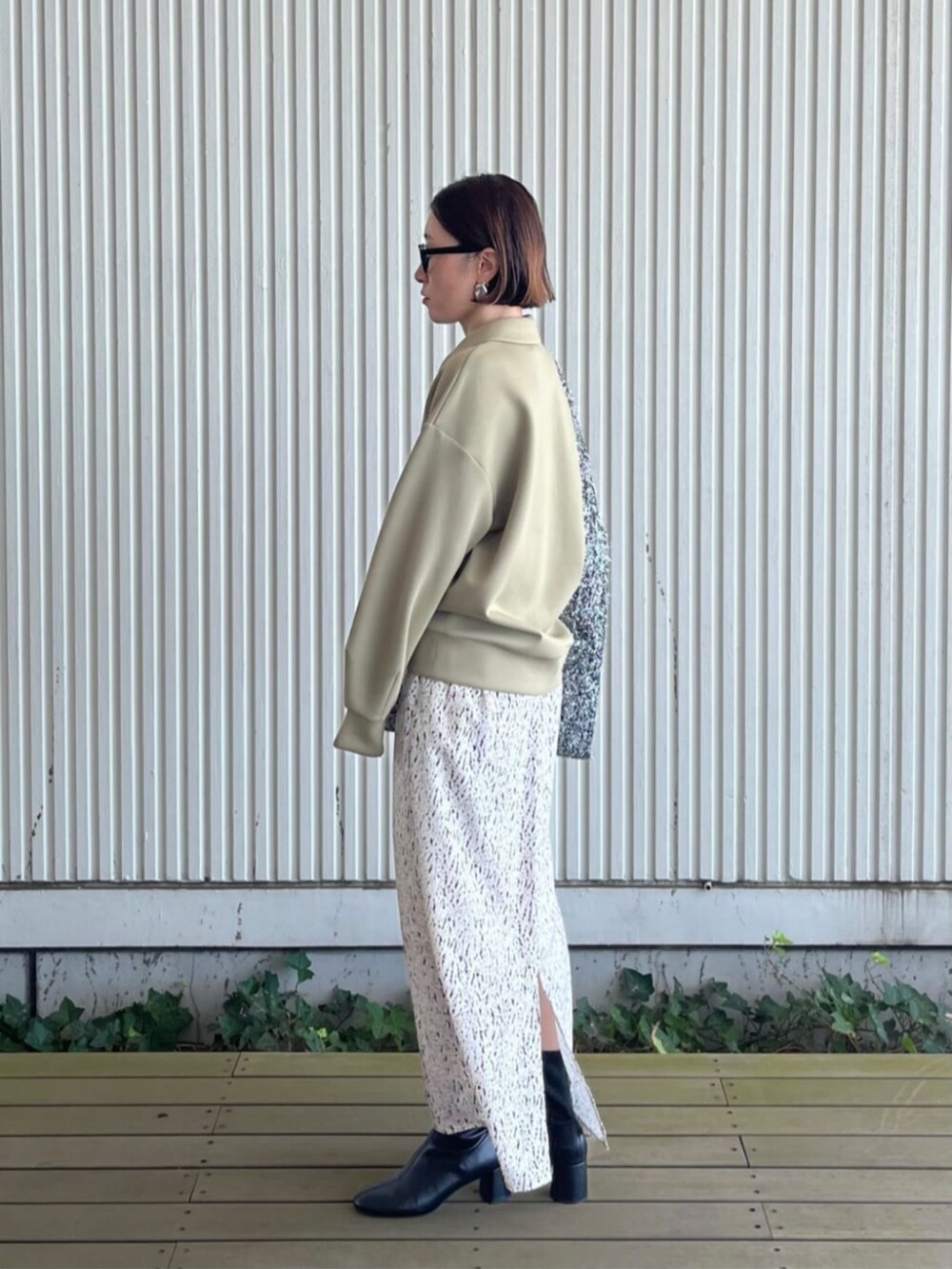 ホワイト系のスカート、シルバー系のトートバッグ、グリーン系のTシャツ/カットソーを着用したレディースの秋コーディネートの2枚目の写真