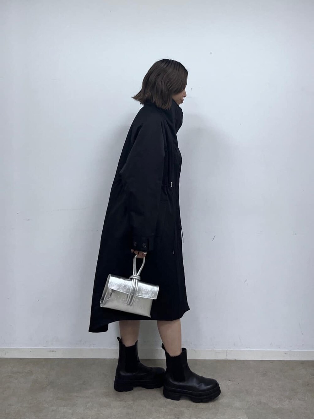 ブラック系のモッズコート、ホワイト系のニット/セーター、ブラック系のその他パンツを着用したレディースの秋コーディネートの4枚目の写真