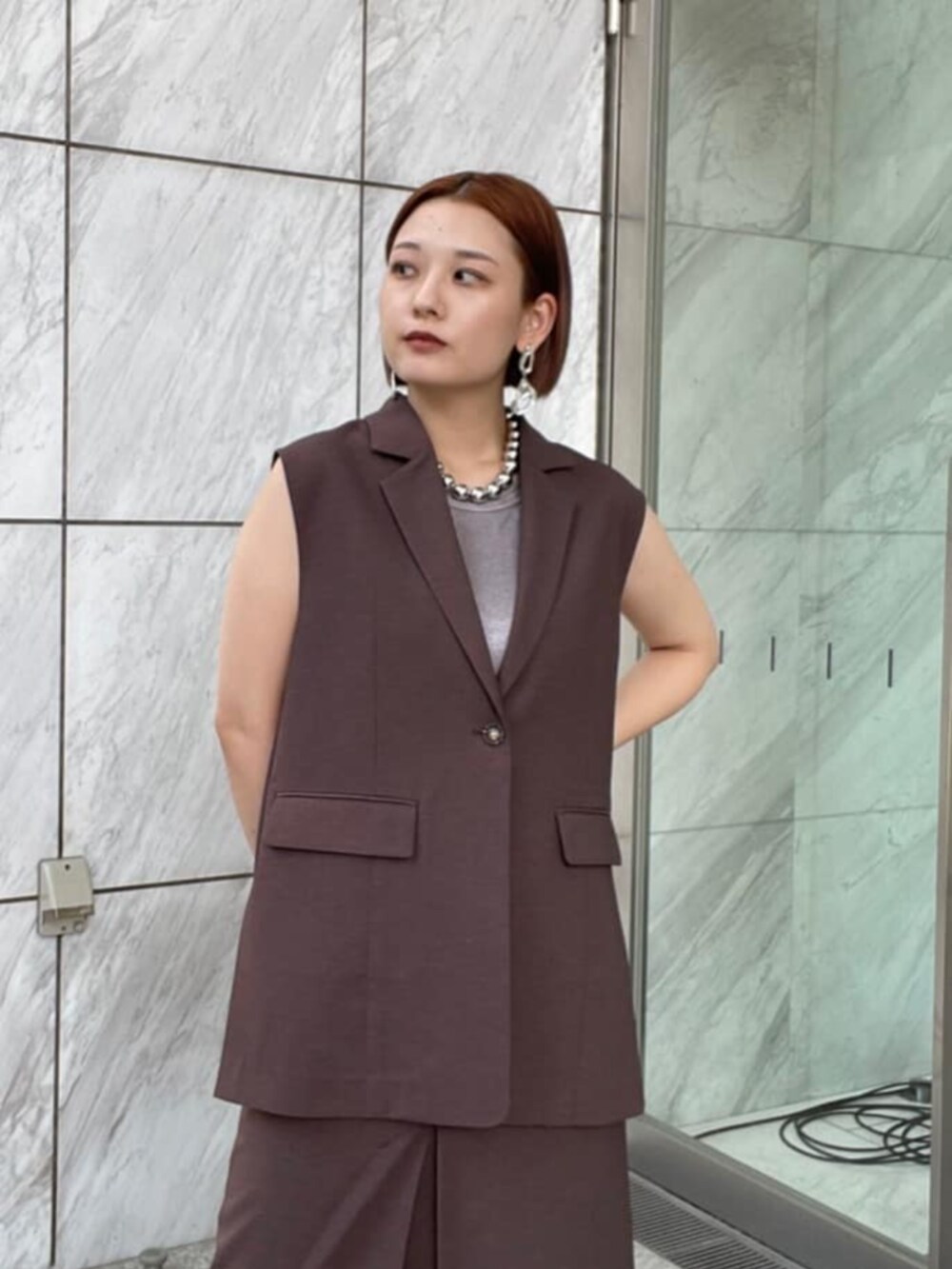 シルバー系のタンクトップ、ブラウン系のベスト、ブラウン系のスカートを着用したレディースの夏コーディネートの4枚目の写真