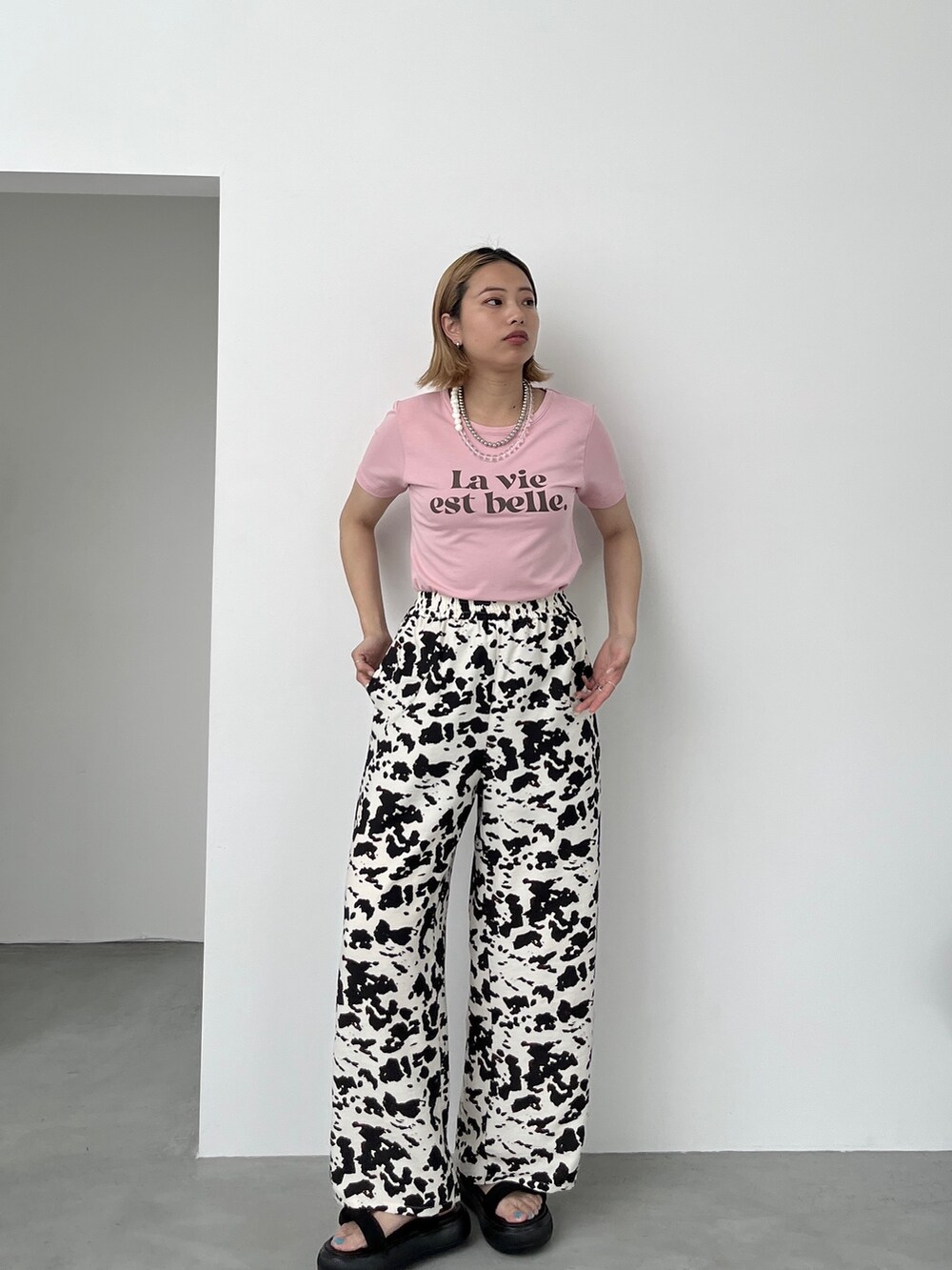 ピンク系のTシャツ/カットソー、ベージュ系のその他パンツ、ブラック系のサンダルを着用したレディースの夏コーディネートの2枚目の写真