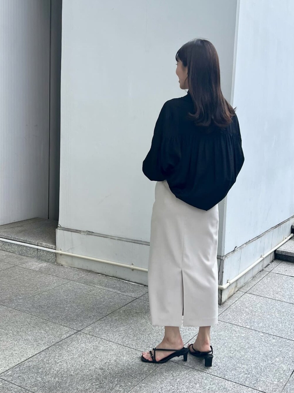 ブラック系のサンダル、ベージュ系のスカート、ブラック系のシャツ/ブラウスを着用したレディースの夏コーディネートの2枚目の写真