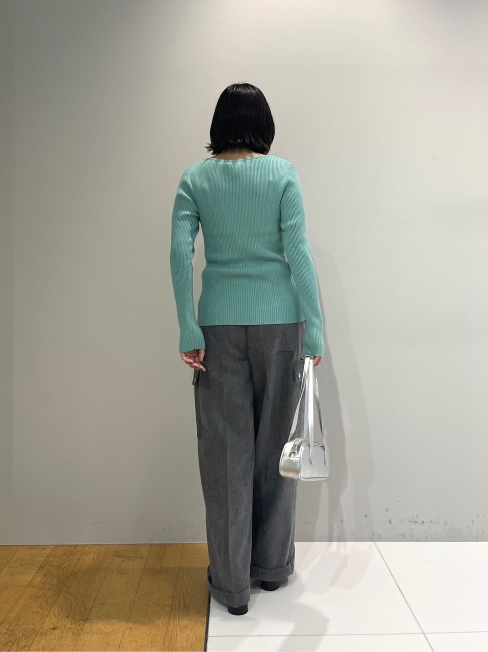 グリーン系のニット/セーター、グレー系のその他パンツ、シルバー系のハンドバッグを着用したレディースの秋コーディネートの3枚目の写真