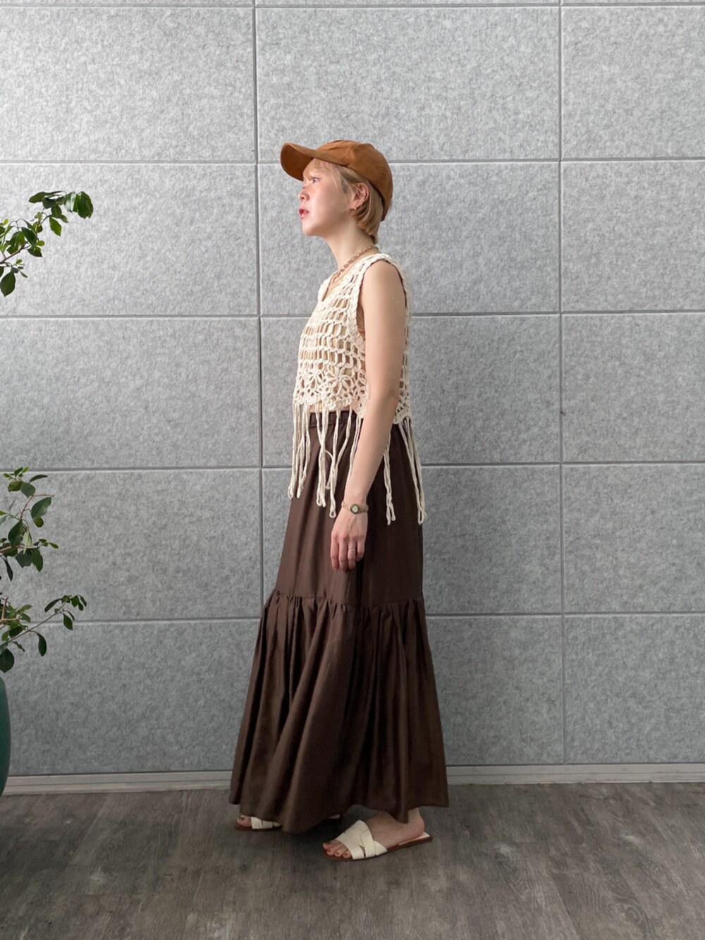 ブラウン系のスカート、ホワイト系のベスト、ゴールド系のタンクトップを着用したレディースの春コーディネートの6枚目の写真