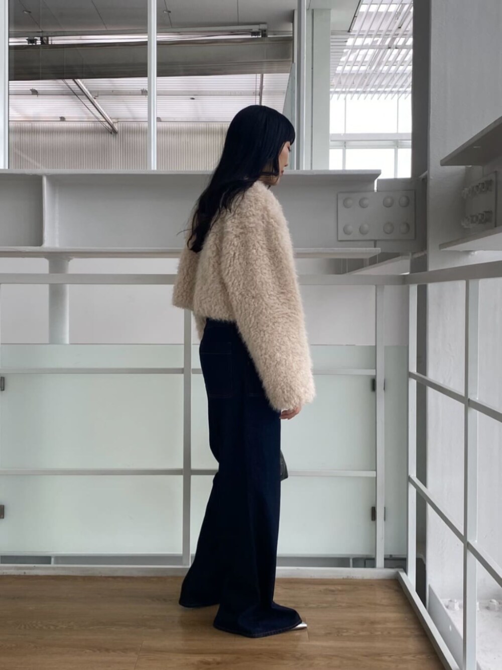 ブルー系のデニムパンツ、ブラック系のTシャツ/カットソー、ブラック系のハンドバッグを着用したレディースの秋コーディネートの3枚目の写真