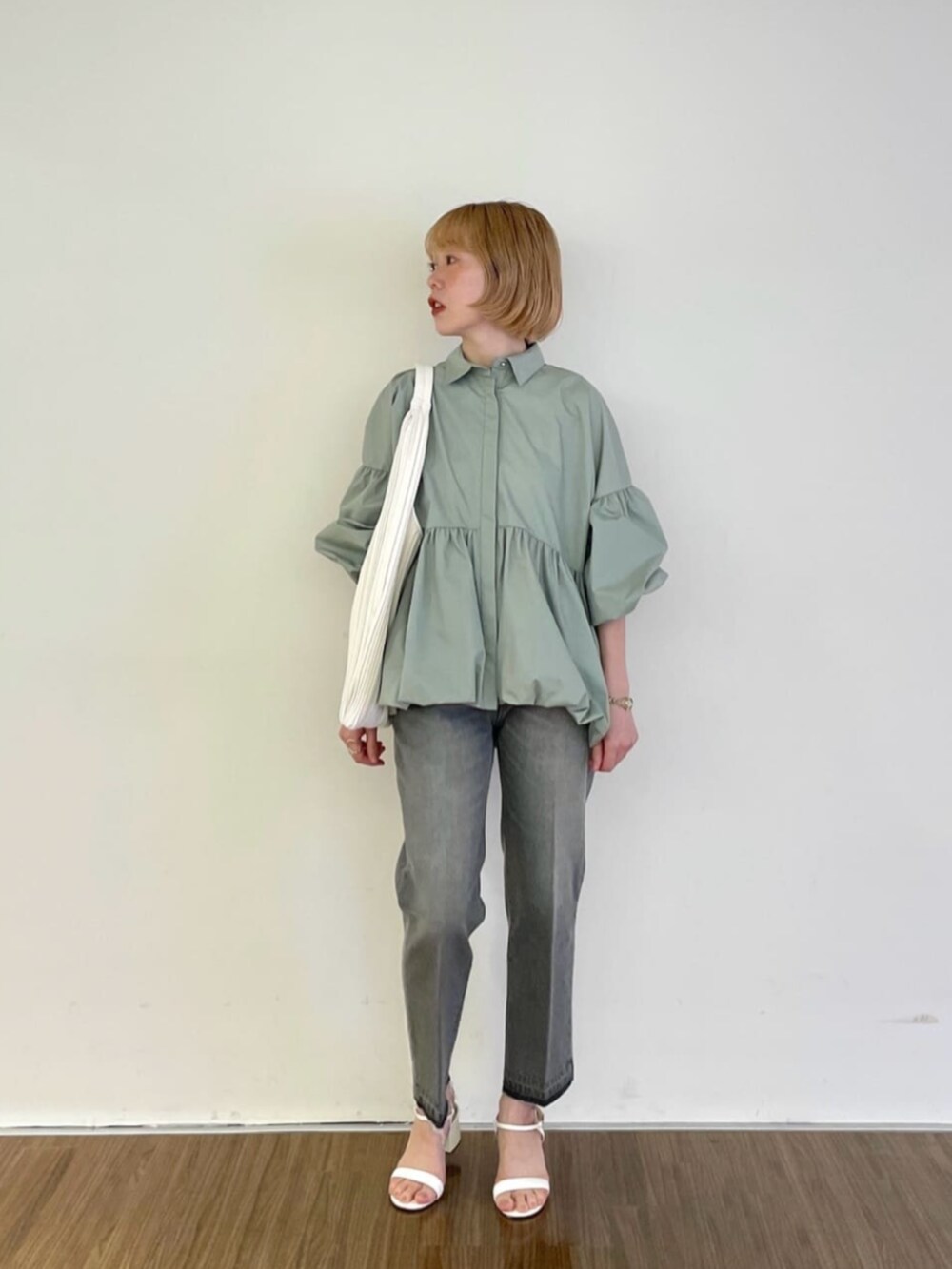 グレー系のデニムパンツ、グリーン系のシャツ/ブラウス、ホワイト系のトートバッグを着用したレディースの春コーディネートの2枚目の写真
