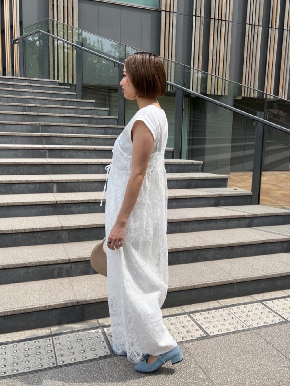 ホワイト系のデニムパンツ、ベージュ系のハンドバッグ、ホワイト系のワンピースを着用したレディースの春コーディネートの2枚目の写真