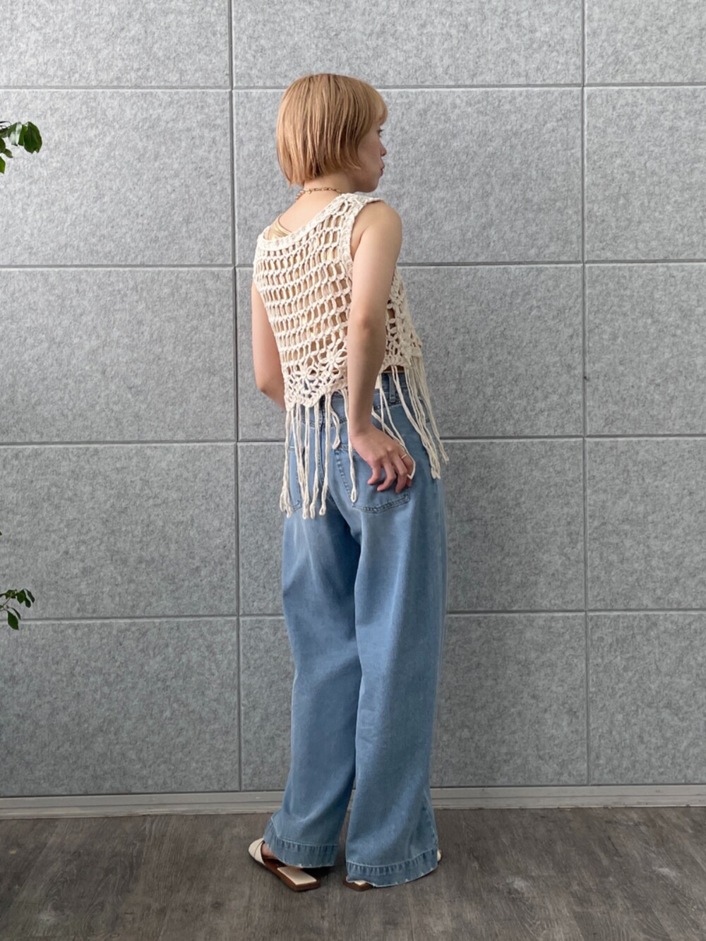 ホワイト系のベスト、ゴールド系のタンクトップ、ブルー系のデニムパンツを着用したレディースの春コーディネートの3枚目の写真