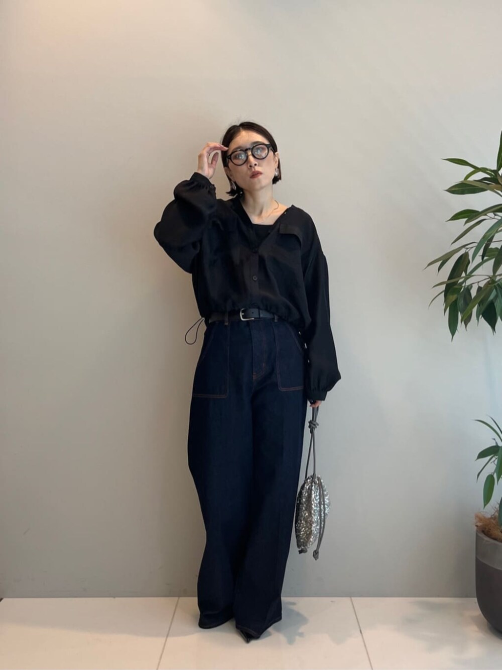 シルバー系のショルダーバッグ、ブルー系のデニムパンツ、ブラック系のシャツ/ブラウスを着用したレディースの秋コーディネートの3枚目の写真