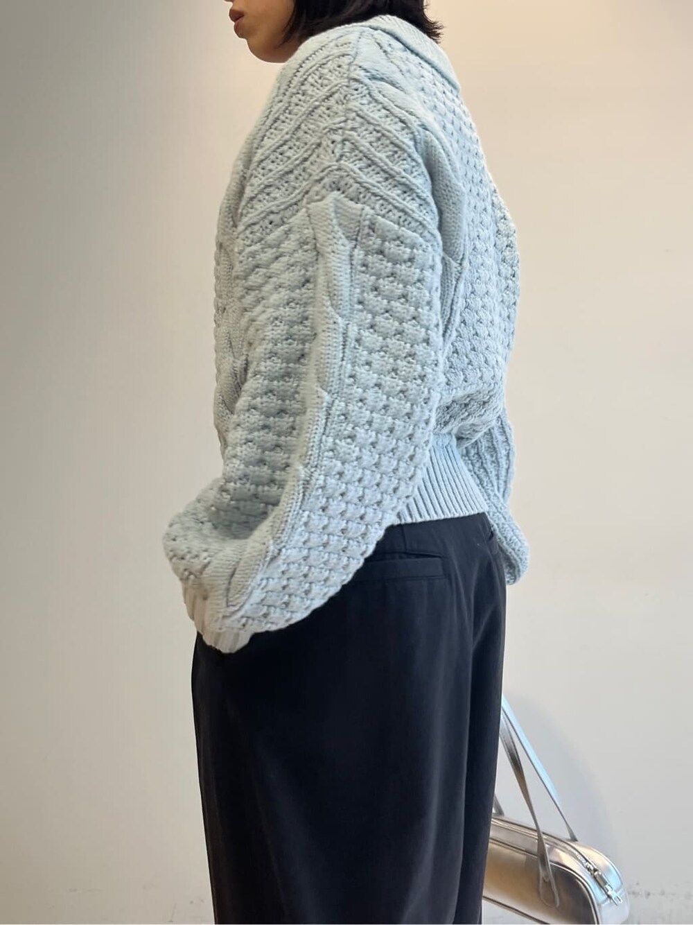 ブルー系のニット/セーター、ブラック系のその他パンツ、シルバー系のハンドバッグを着用したレディースの秋コーディネートの6枚目の写真
