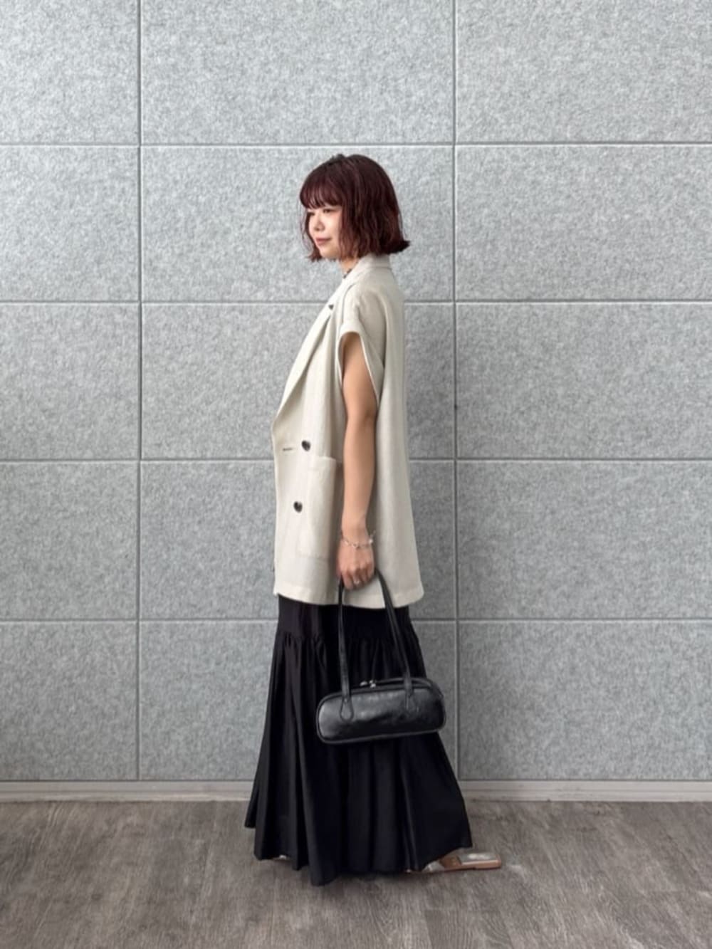 グレー系のテーラードジャケット、ブラック系のスカート、ブラック系のハンドバッグを着用したレディースの夏コーディネートの2枚目の写真