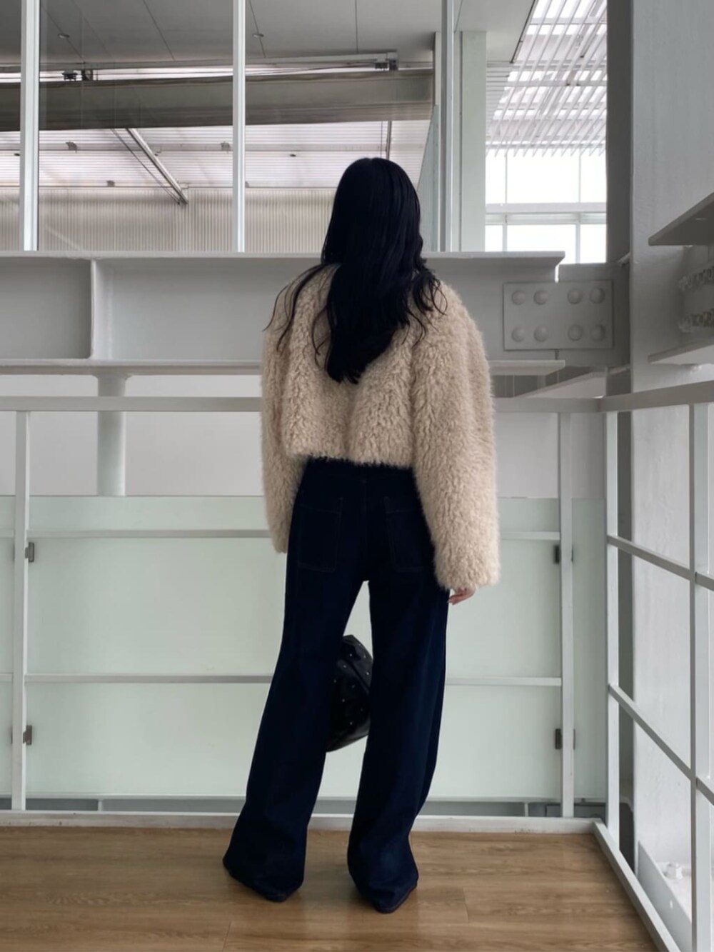 ブルー系のデニムパンツ、ブラック系のTシャツ/カットソー、ブラック系のハンドバッグを着用したレディースの秋コーディネートの2枚目の写真