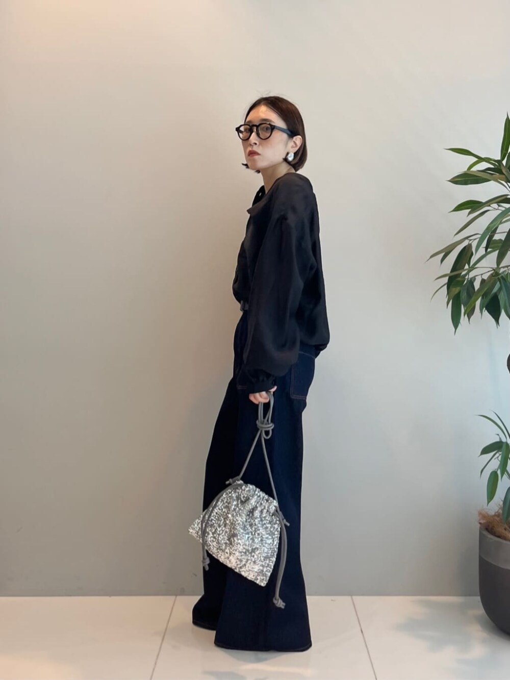 シルバー系のショルダーバッグ、ブルー系のデニムパンツ、ブラック系のシャツ/ブラウスを着用したレディースの秋コーディネートの4枚目の写真