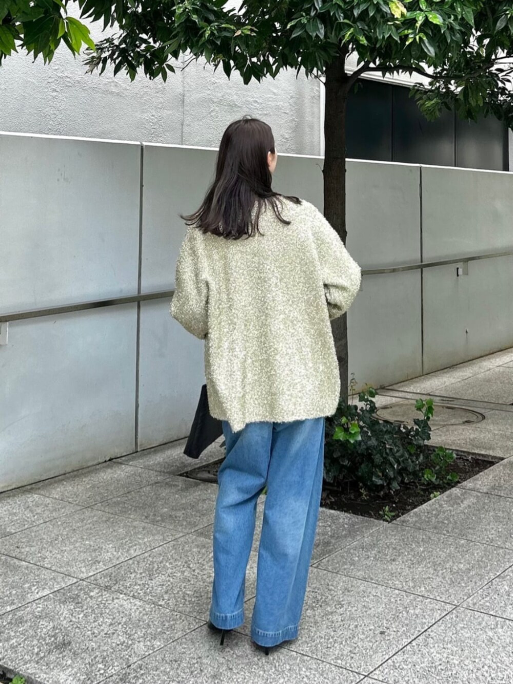 ブラック系のニット/セーター、ブルー系のデニムパンツ、ゴールド系のカーディガン/ボレロを着用したレディースの秋コーディネートの2枚目の写真