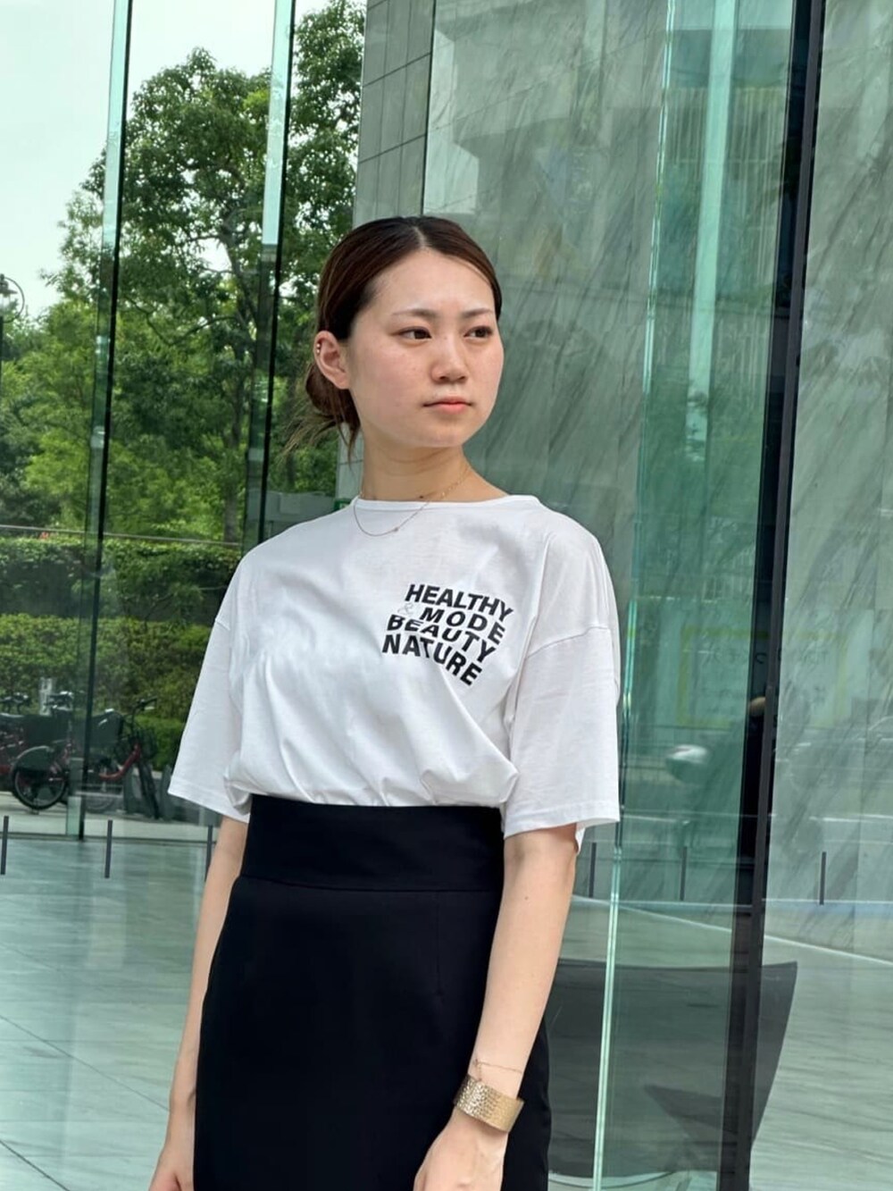 ブラック系のスカート、ホワイト系のTシャツ/カットソー、ブラック系のサンダルを着用したレディースの夏コーディネートの3枚目の写真