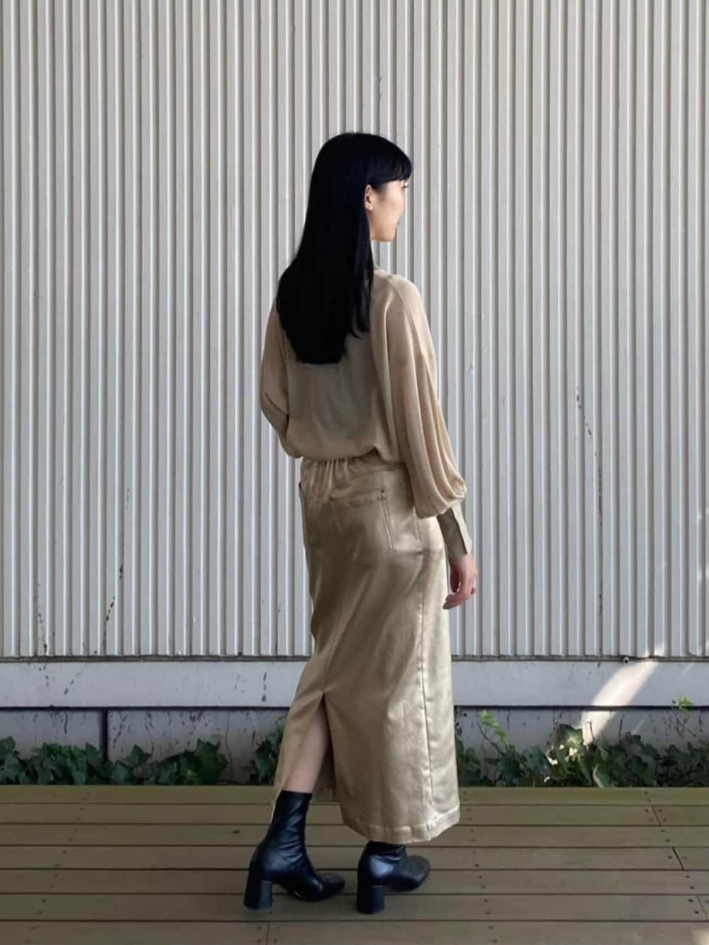 ブラック系のブルゾン、ゴールド系のスカート、ベージュ系のニット/セーターを着用したレディースの秋コーディネートの4枚目の写真