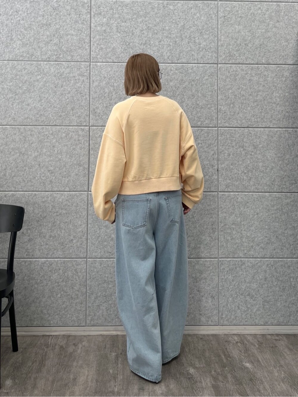 オレンジ系のスウェット、ブルー系のデニムパンツを着用したレディースの春コーディネートの4枚目の写真
