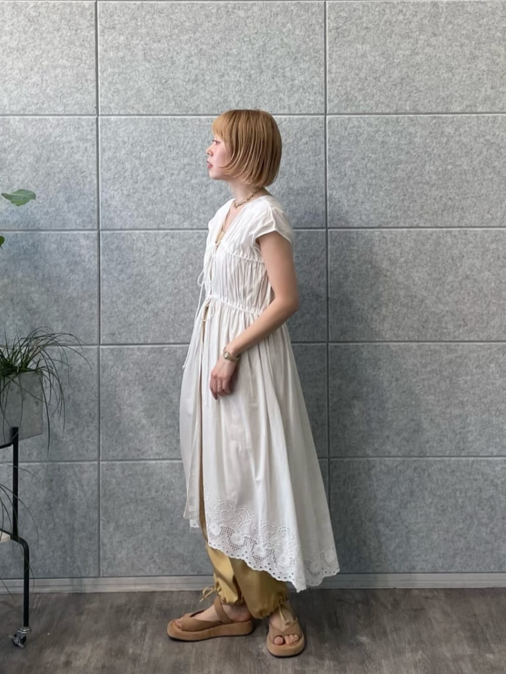 ゴールド系のチューブトップ、ホワイト系のワンピース、ベージュ系のその他パンツを着用したレディースの春コーディネートの3枚目の写真