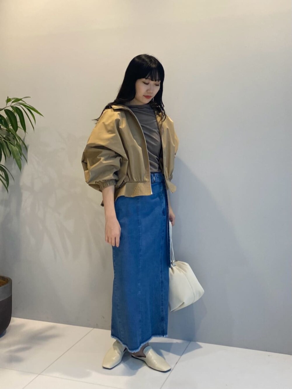 ブルー系のデニムスカート、ベージュ系のブルゾン、ベージュ系のTシャツ/カットソーを着用したレディースの秋コーディネートの2枚目の写真