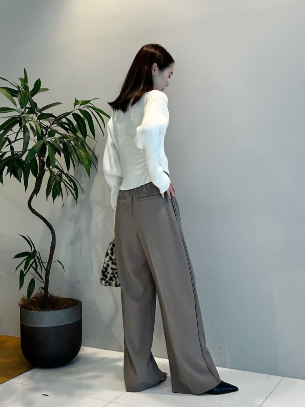 ブラウン系のハンドバッグ、ブラウン系のその他パンツ、ホワイト系のニット/セーターを着用したレディースの秋コーディネートの2枚目の写真