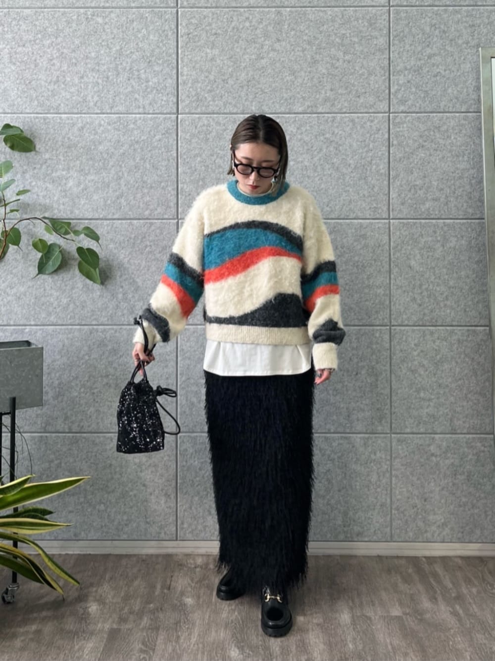 ブラック系のショルダーバッグ、ホワイト系のTシャツ/カットソー、ブラック系のスカートを着用したレディースの冬コーディネートの2枚目の写真