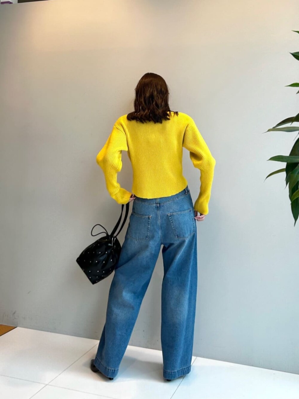 ブラック系のハンドバッグ、ブルー系のデニムパンツ、イエロー系のニット/セーターを着用したレディースの秋コーディネートの3枚目の写真