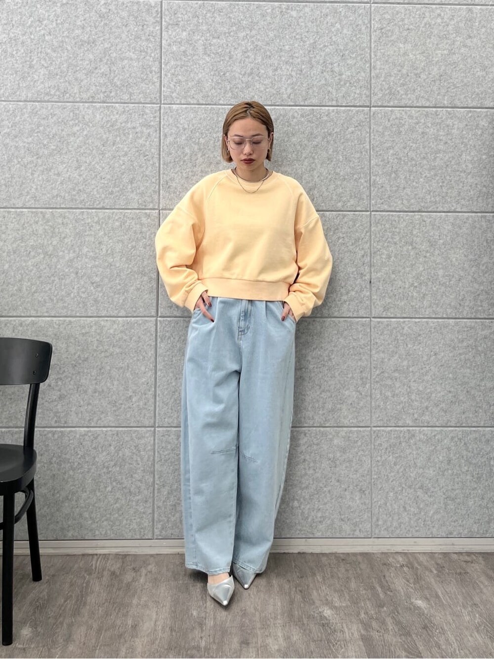 オレンジ系のスウェット、ブルー系のデニムパンツを着用したレディースの春コーディネートの2枚目の写真