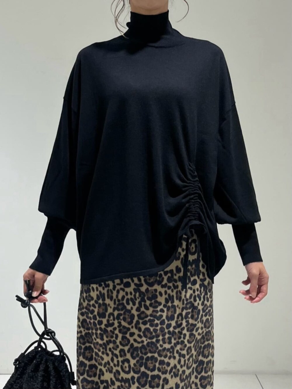 ブラック系のショルダーバッグ、ブラック系のニット/セーター、ブラウン系のスカートを着用したレディースの秋コーディネートの3枚目の写真