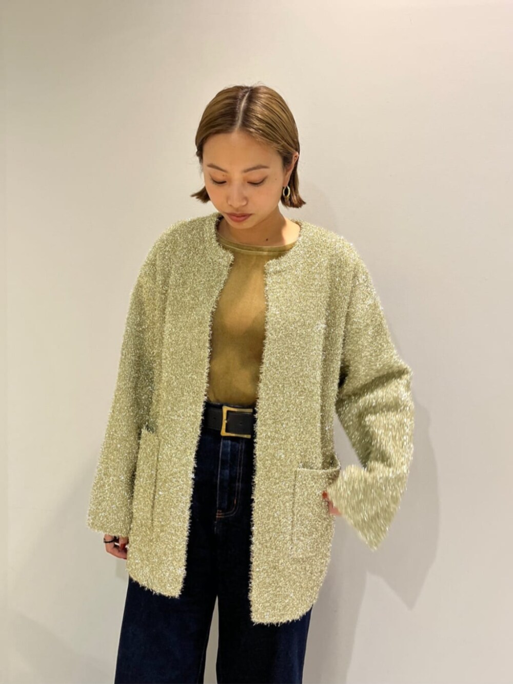 ブルー系のデニムパンツ、ベージュ系のTシャツ/カットソー、ゴールド系のカーディガン/ボレロを着用したレディースの秋コーディネートの3枚目の写真