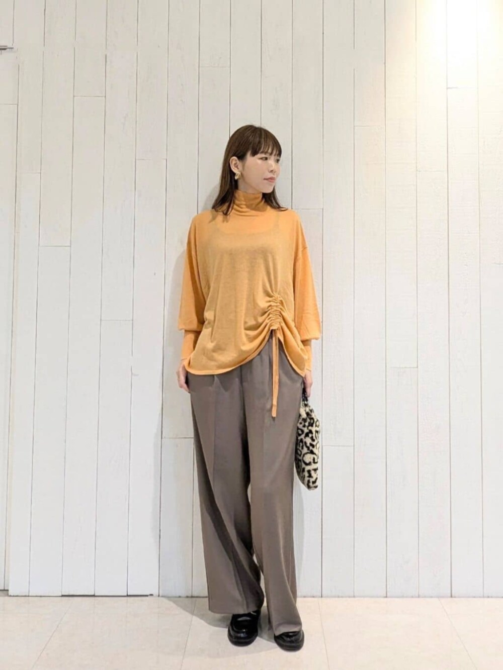 ブラウン系のハンドバッグ、ブラウン系のその他パンツ、オレンジ系のニット/セーターを着用したレディースの秋コーディネートの2枚目の写真