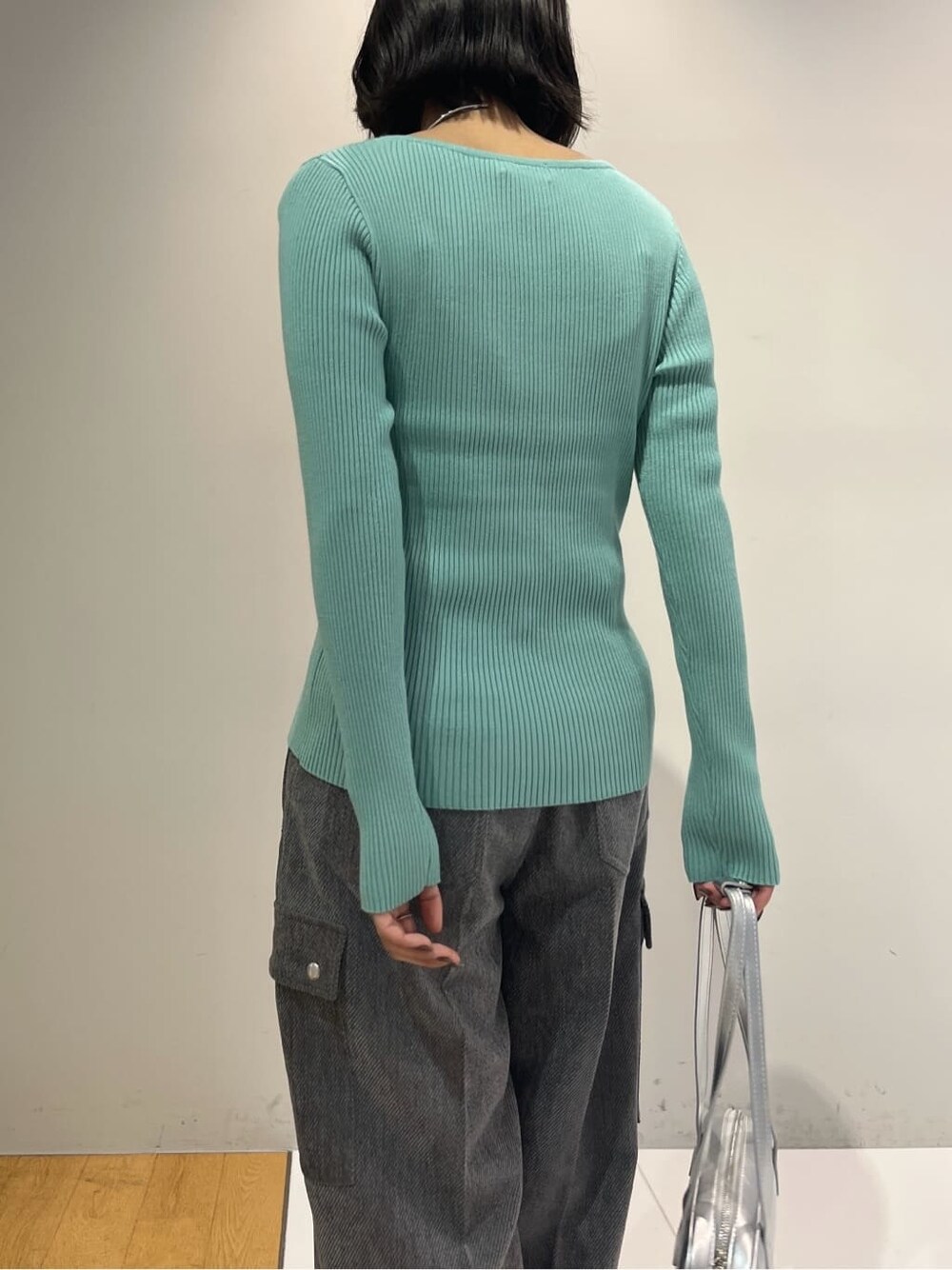 グリーン系のニット/セーター、グレー系のその他パンツ、シルバー系のハンドバッグを着用したレディースの秋コーディネートの6枚目の写真