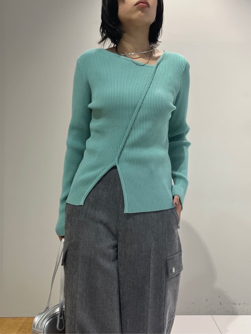 グリーン系のニット/セーター、グレー系のその他パンツ、シルバー系のハンドバッグを着用したレディースの秋コーディネートの4枚目の写真