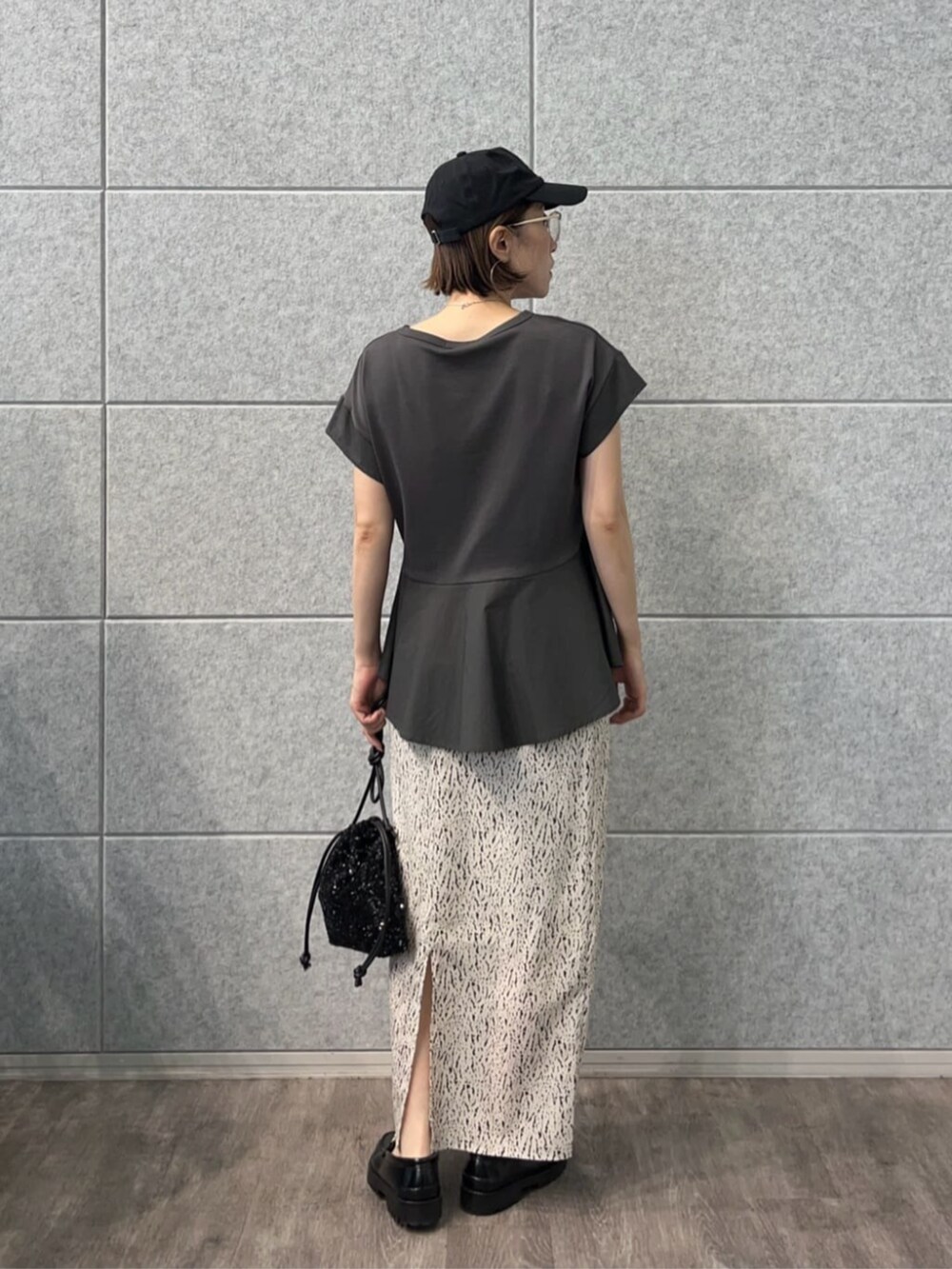 ブラック系のショルダーバッグ、グレー系のTシャツ/カットソー、ホワイト系のスカートを着用したレディースの秋コーディネートの2枚目の写真