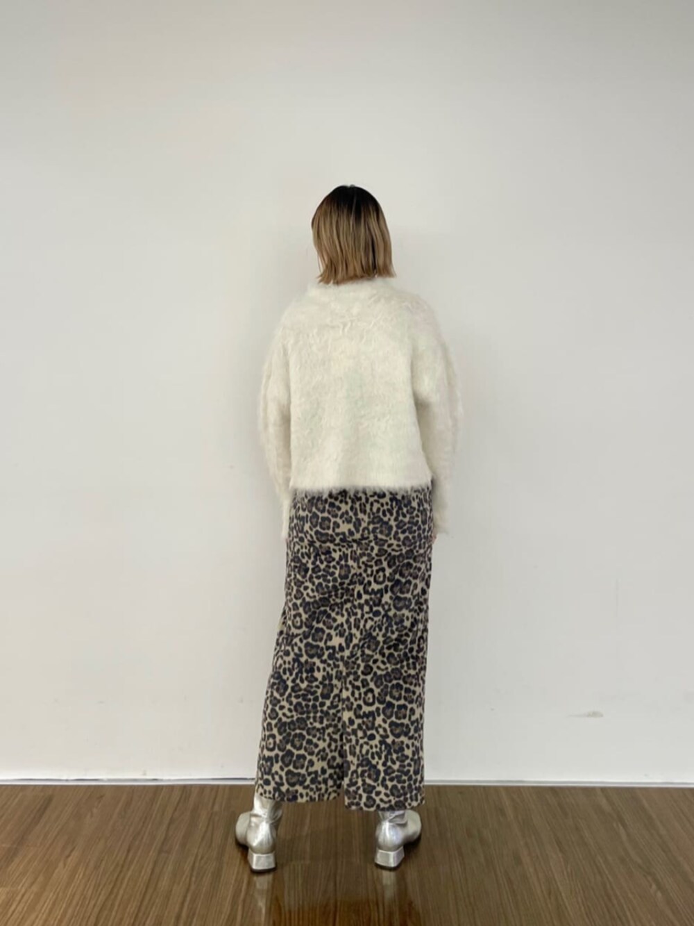 ブラウン系のスカート、ホワイト系のニット/セーター、ゴールド系のネックレスを着用したレディースの秋コーディネートの2枚目の写真