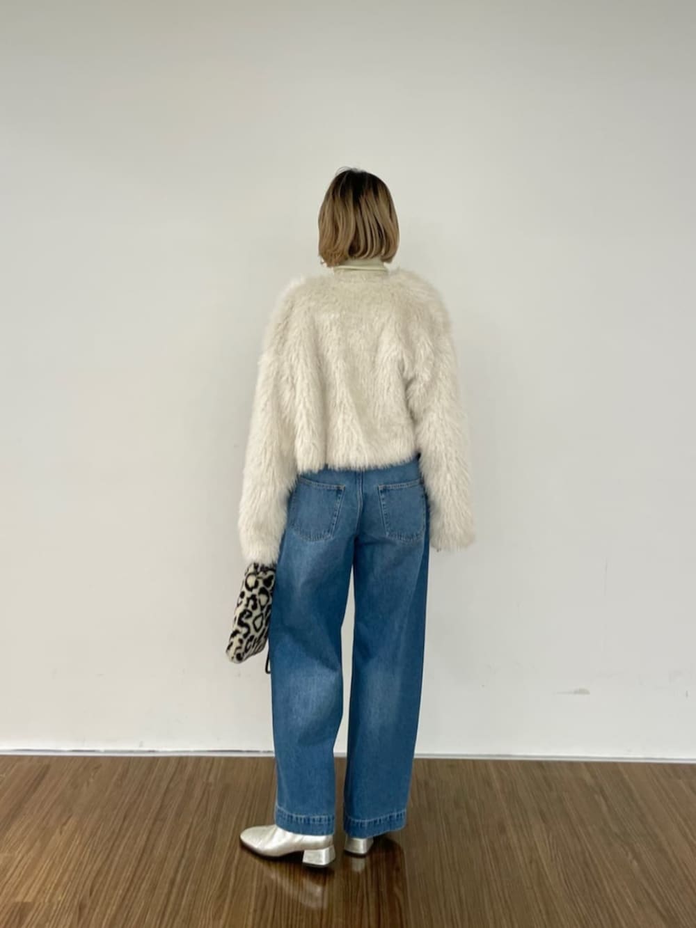 ブラウン系のハンドバッグ、ブルー系のデニムパンツ、ゴールド系のニット/セーターを着用したレディースの秋コーディネートの2枚目の写真