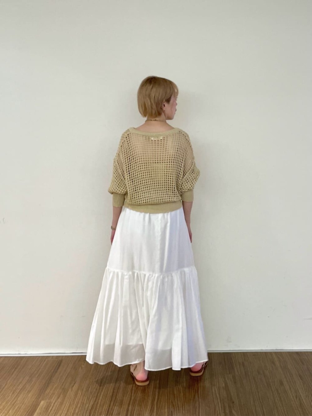 ホワイト系のスカート、ゴールド系のチューブトップ、ベージュ系のカーディガン/ボレロを着用したレディースの春コーディネートの3枚目の写真