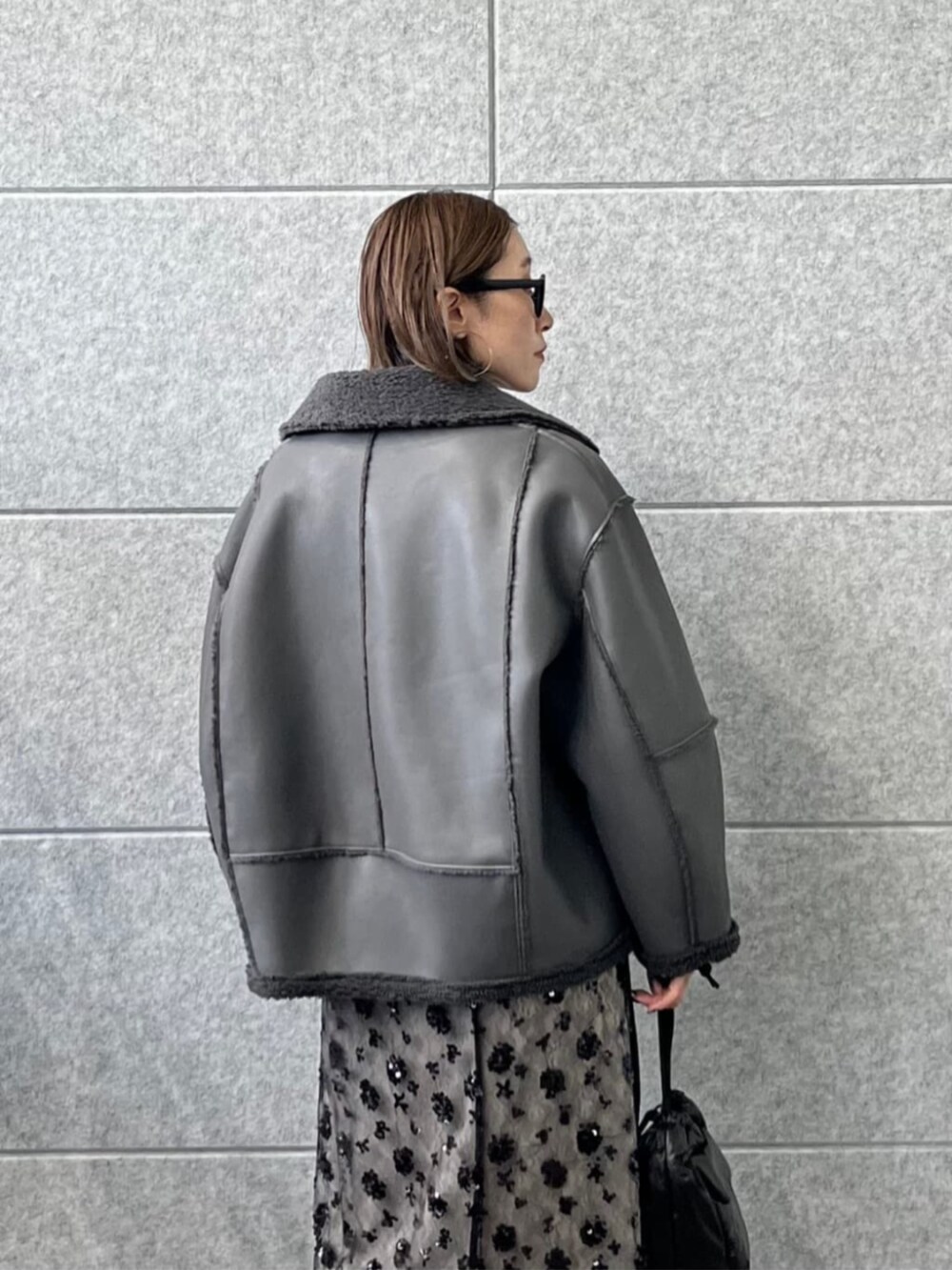 ブラック系のスカート、ホワイト系のニット/セーター、グレー系のブルゾンを着用したレディースの冬コーディネートの2枚目の写真