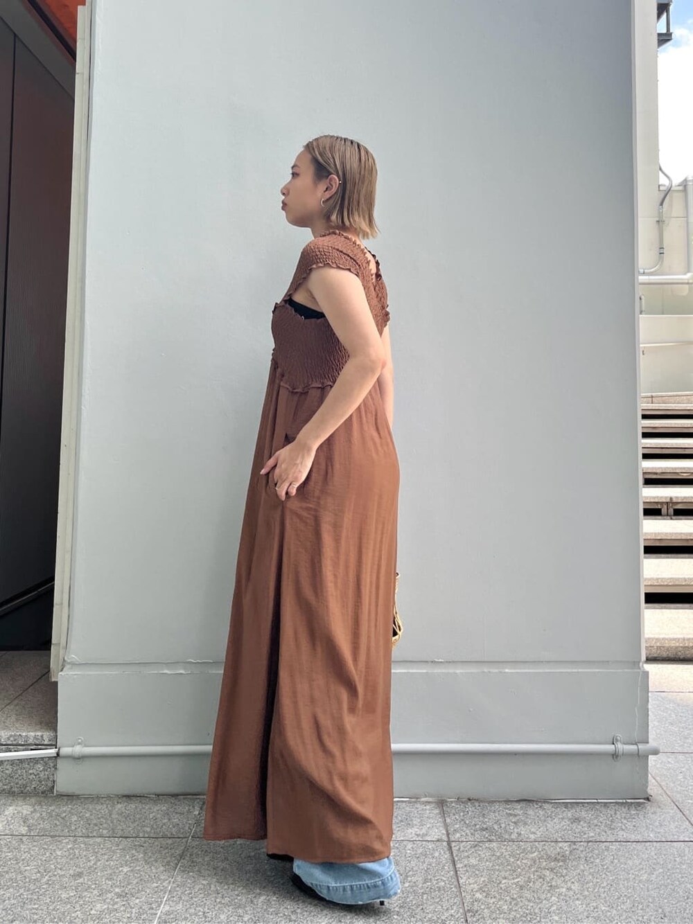 ブラウン系のワンピース、ブルー系のデニムパンツ、ブラック系のハンドバッグを着用したレディースの夏コーディネートの3枚目の写真