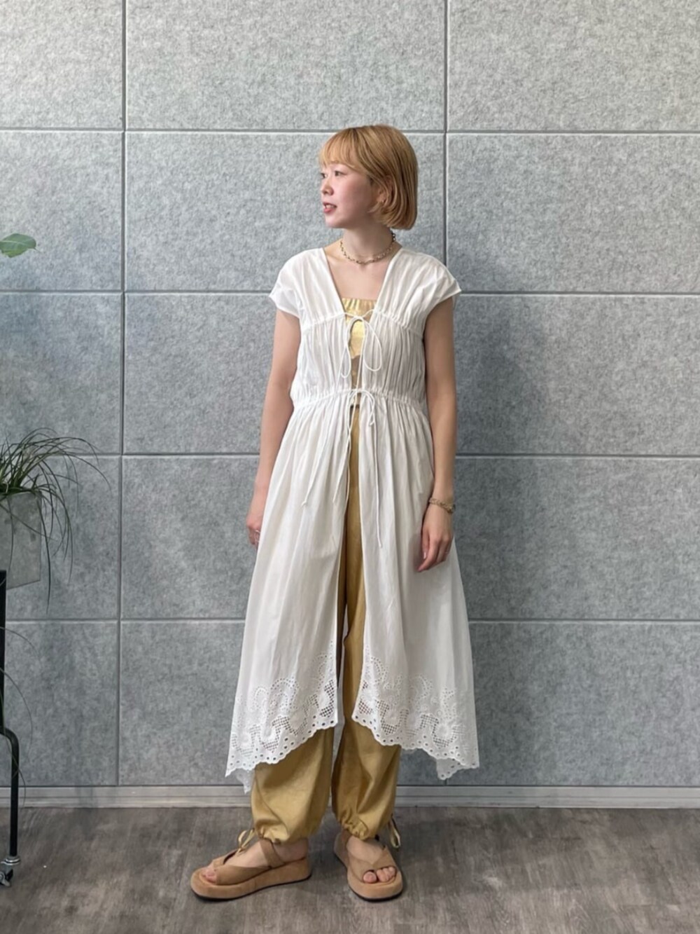 ゴールド系のチューブトップ、ホワイト系のワンピース、ベージュ系のその他パンツを着用したレディースの春コーディネートの2枚目の写真