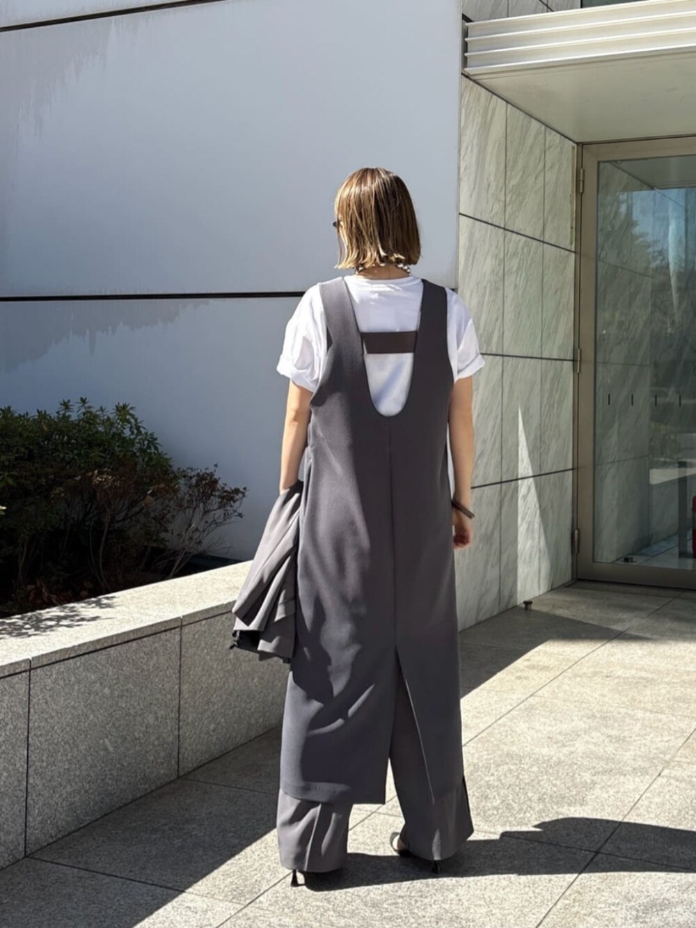 グレー系のその他パンツ、グレー系のワンピース、ホワイト系のTシャツ/カットソーを着用したレディースの春コーディネートの2枚目の写真