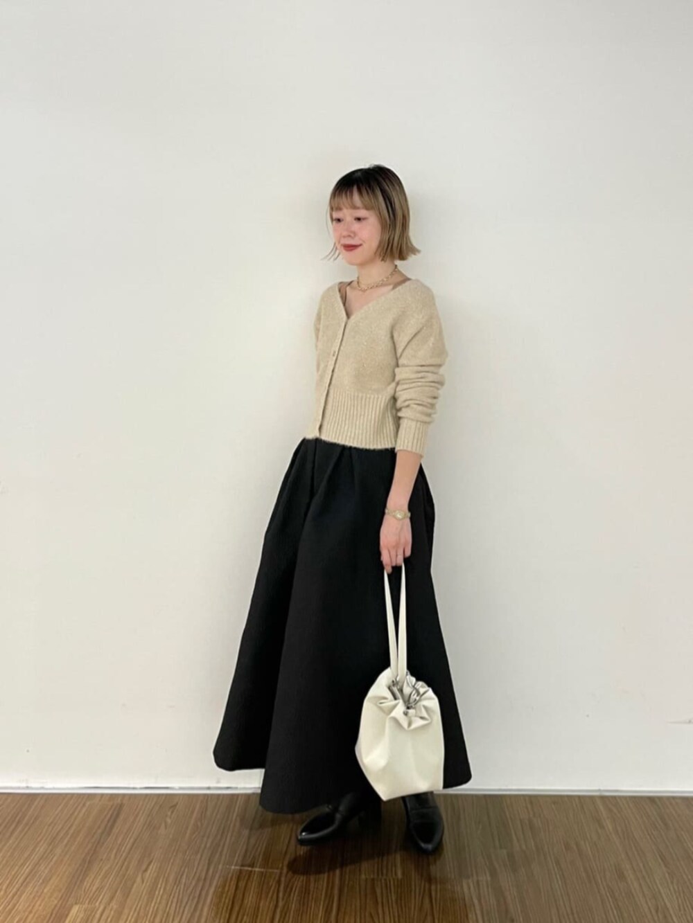 ベージュ系のカーディガン/ボレロ、ブラック系のブーツ、ブラック系のスカートを着用したレディースの秋コーディネートの2枚目の写真