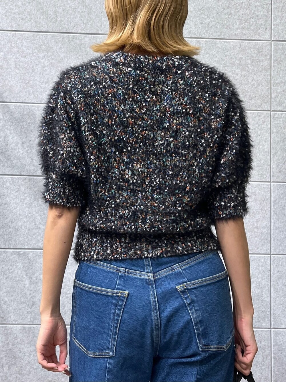 ブラック系のニット/セーター、ブルー系のデニムパンツを着用したレディースの夏コーディネートの9枚目の写真