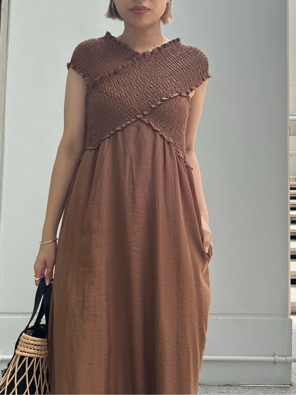 ブラウン系のワンピース、ブルー系のデニムパンツ、ブラック系のハンドバッグを着用したレディースの夏コーディネートの6枚目の写真