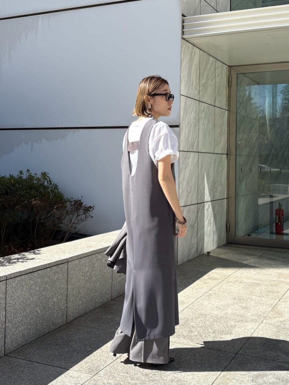 グレー系のその他パンツ、グレー系のワンピース、ホワイト系のTシャツ/カットソーを着用したレディースの春コーディネートの3枚目の写真