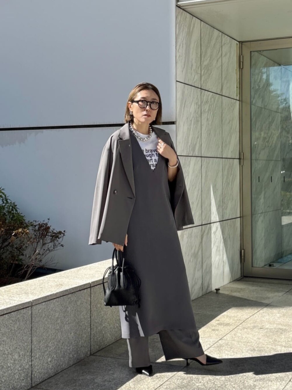 グレー系のその他パンツ、グレー系のワンピース、ホワイト系のTシャツ/カットソーを着用したレディースの春コーディネートの2枚目の写真