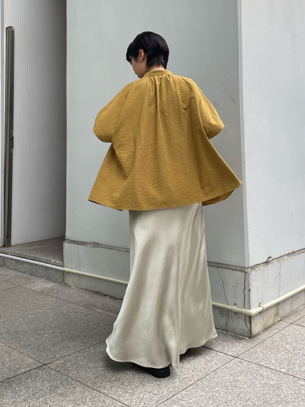 シルバー系のスカート、イエロー系のシャツ/ブラウス、ブラック系のサンダルを着用したレディースの夏コーディネートの3枚目の写真