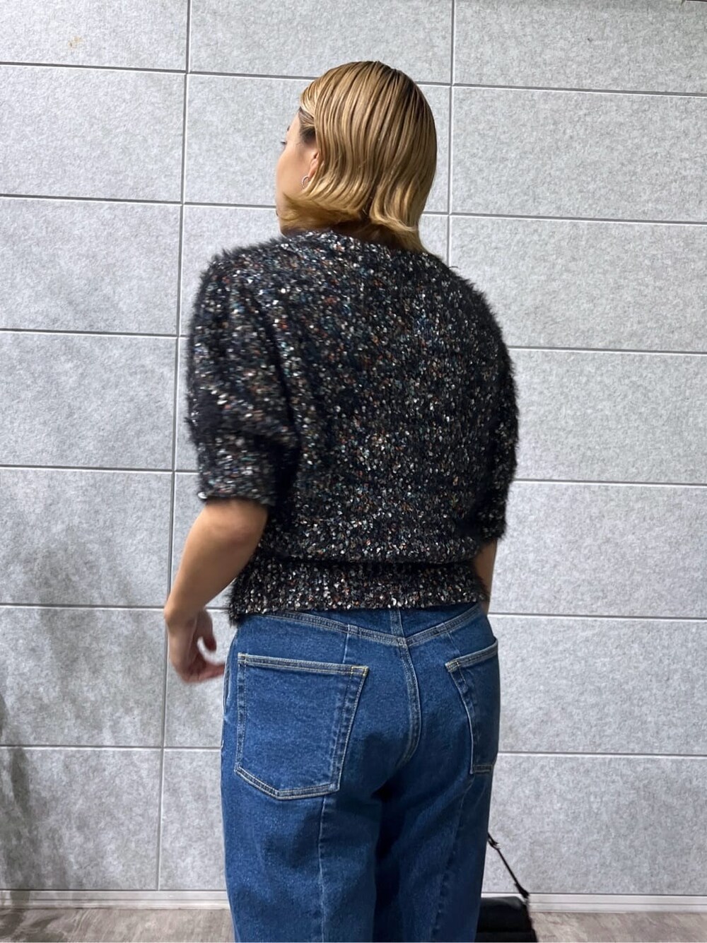 ブラック系のニット/セーター、ブルー系のデニムパンツを着用したレディースの夏コーディネートの7枚目の写真
