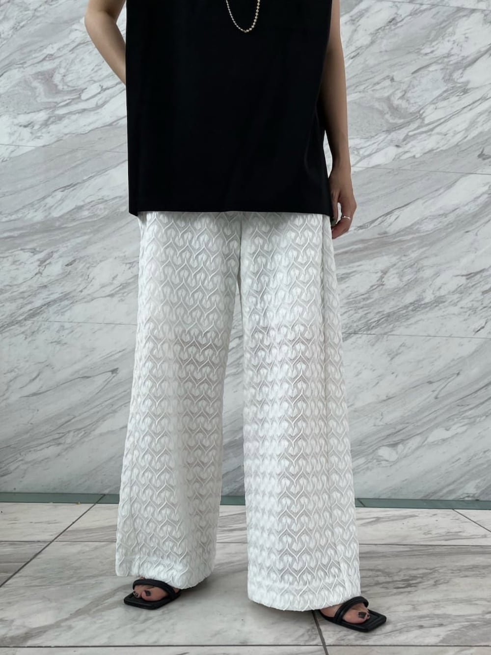 ブラック系のTシャツ/カットソー、ホワイト系のその他パンツ、ブラック系のサンダルを着用したレディースの夏コーディネートの3枚目の写真