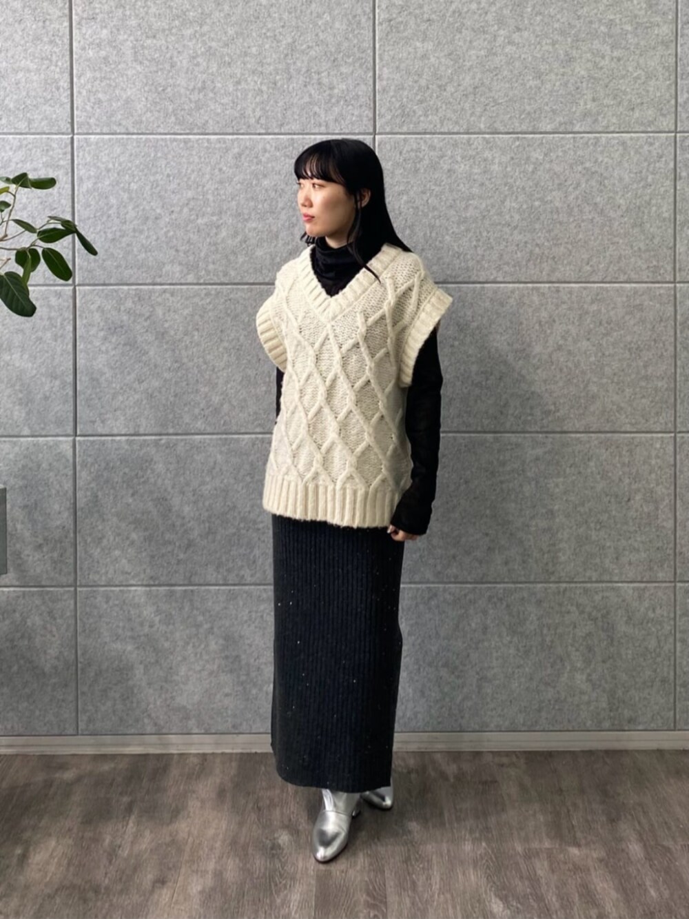 グレー系のスカート、ブラック系のTシャツ/カットソー、ホワイト系のベストを着用したレディースの冬コーディネートの2枚目の写真