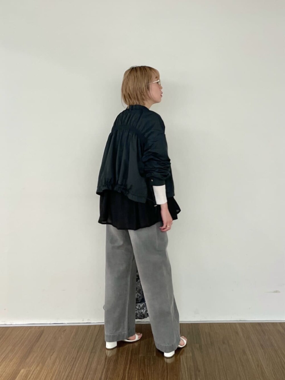 グレー系のデニムパンツ、ホワイト系のニット/セーター、グレー系のブルゾンを着用したレディースの春コーディネートの4枚目の写真